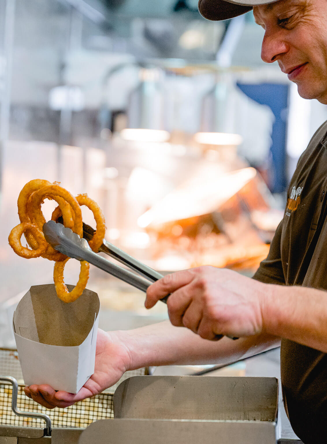 Man serves fried onion rings in a paper bag in restaurant
